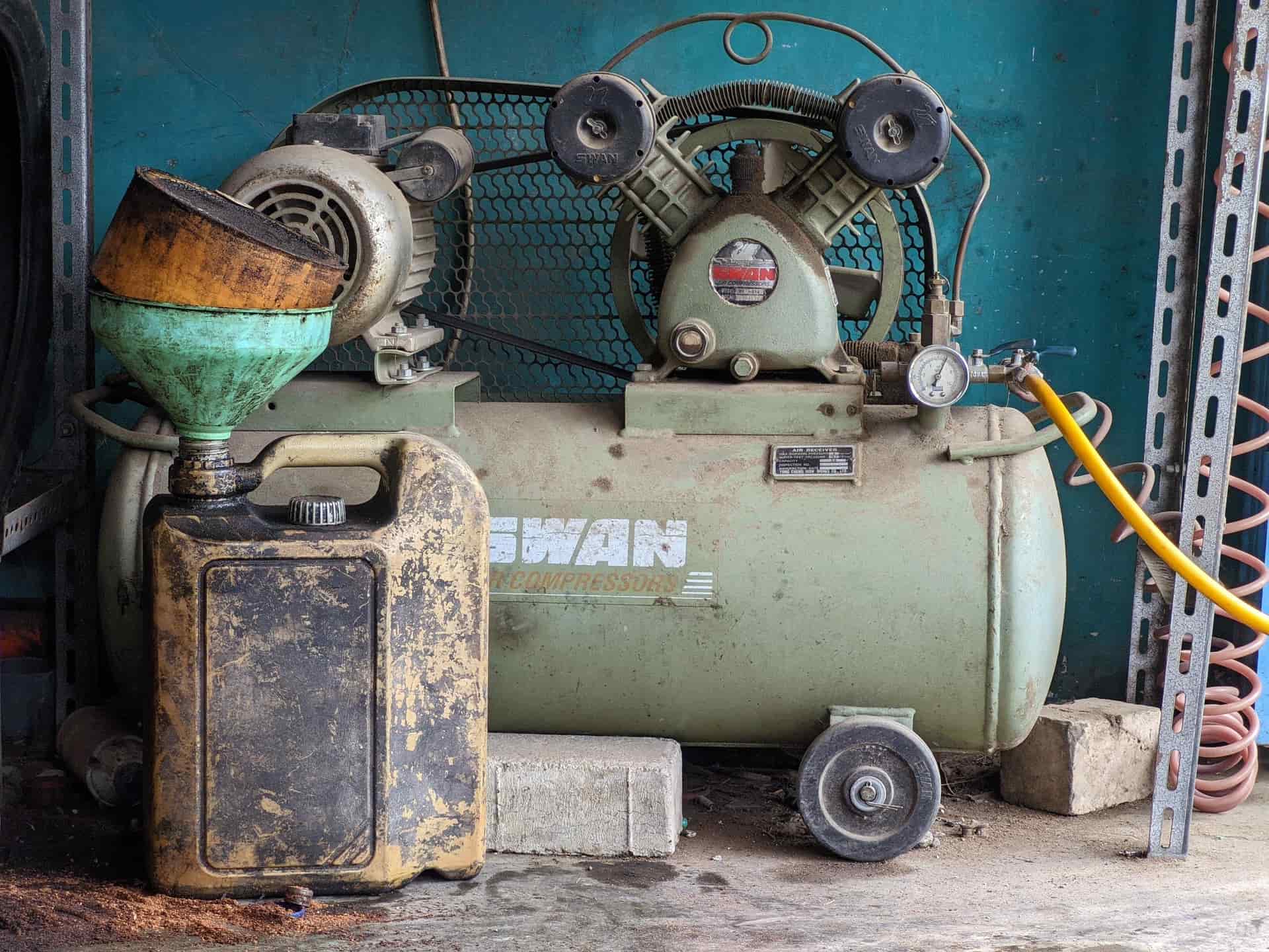 An air compressor with a tank standing in a workshop