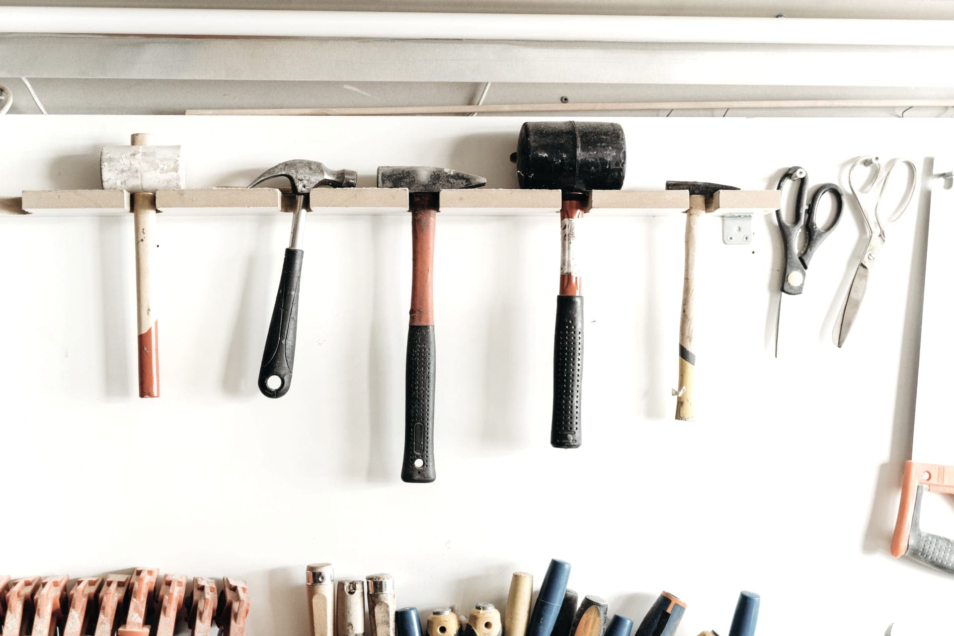 A bright, orderly workshop wall with hand tools hung in a row