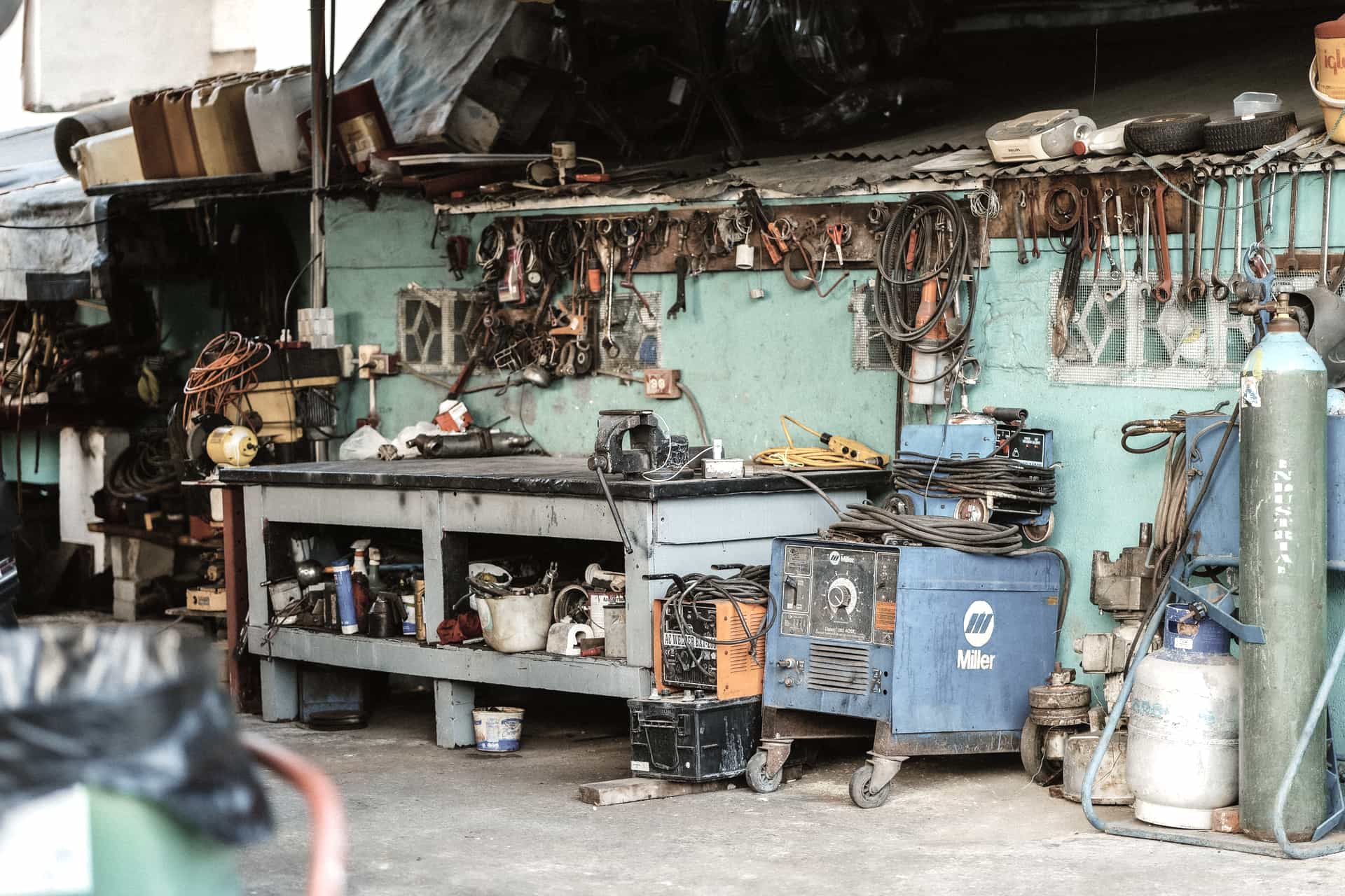 A compact wire-feed welding machine standing on a workbench in a domestic garage