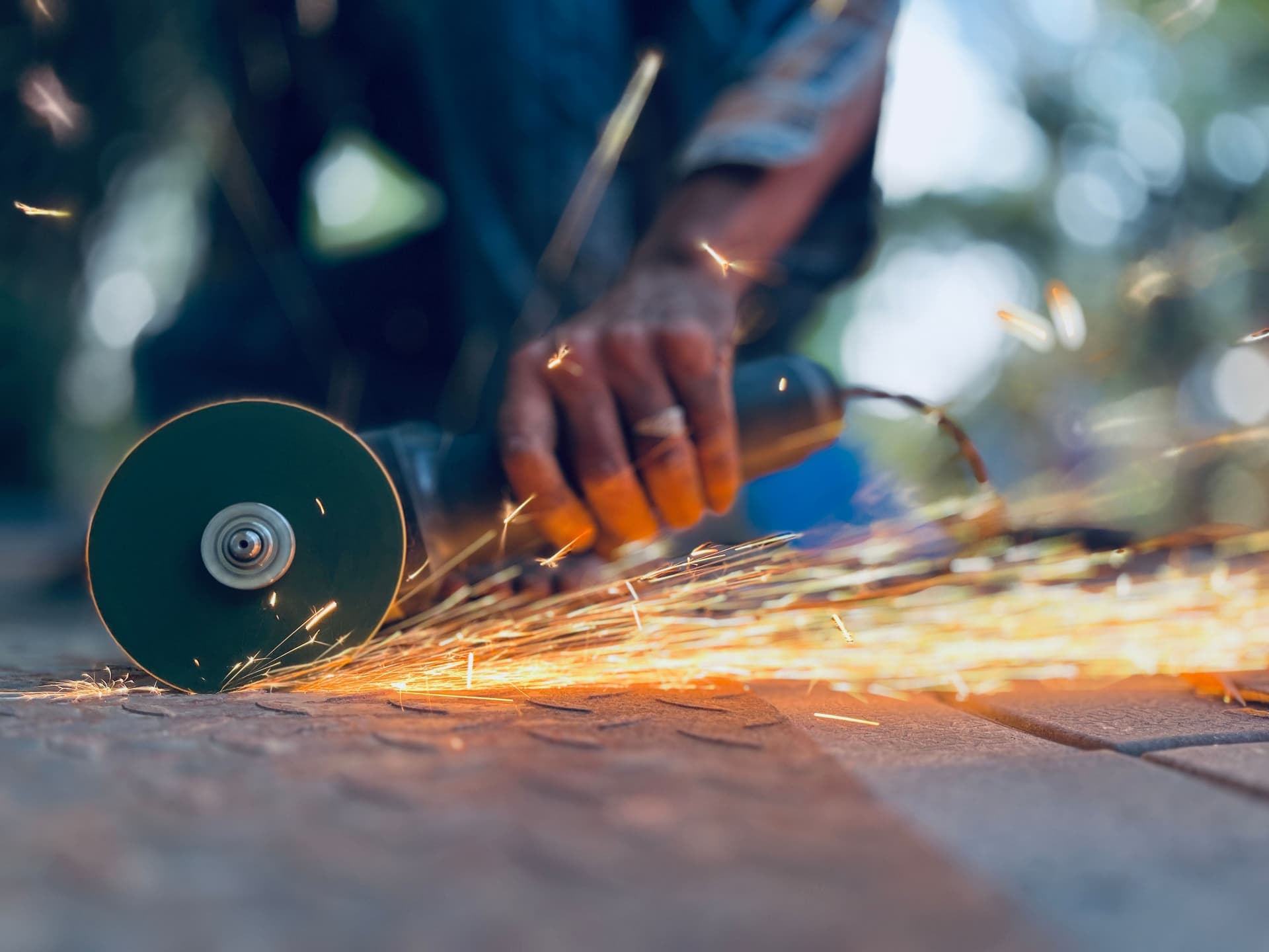 An angle grinder with a cut-off disc fitted, lying on a bench beside steel offcuts