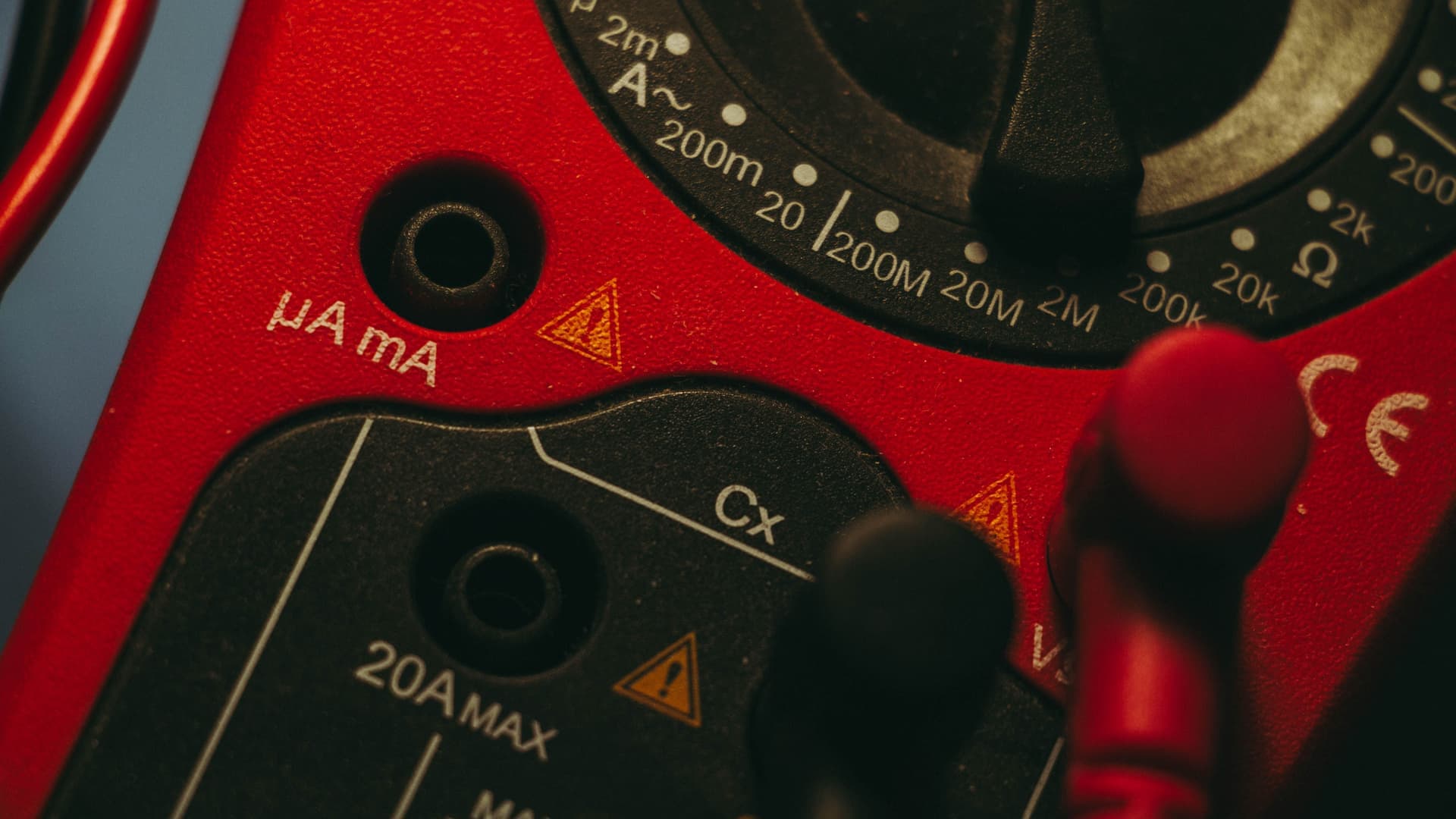 A digital clamp meter resting on a workbench beside a power cable