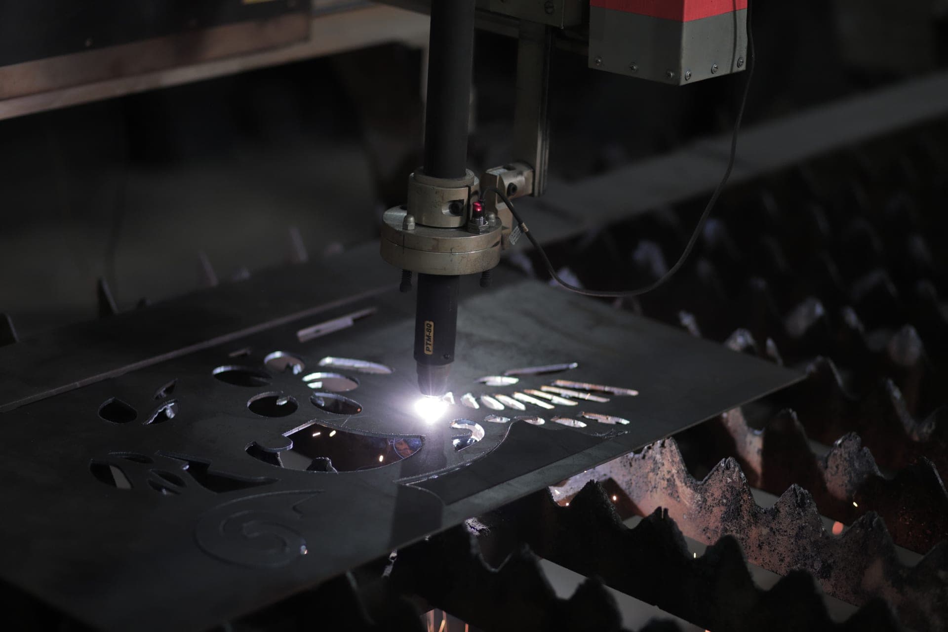 A plasma cutter with a coiled torch lead beside freshly cut steel