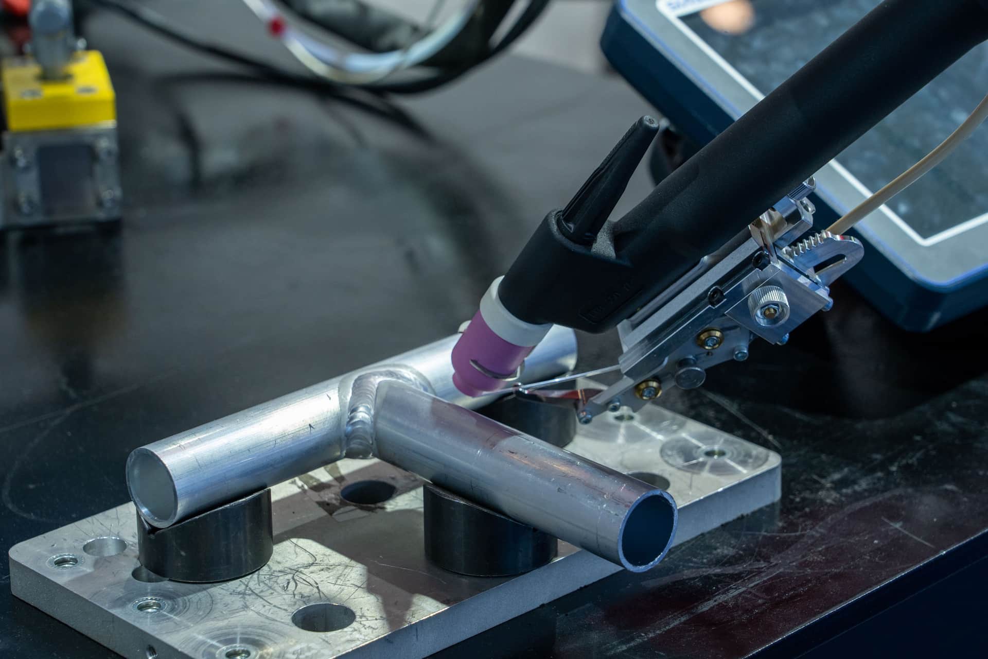 An AC/DC TIG welder with a torch and foot pedal on a clean workbench